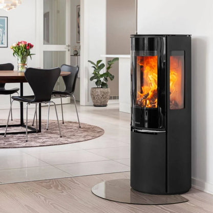 Elegant Aduro 22.5 Lux braskamin med helglas och sidoglas placerad på glasskiva i ett ljust hem
