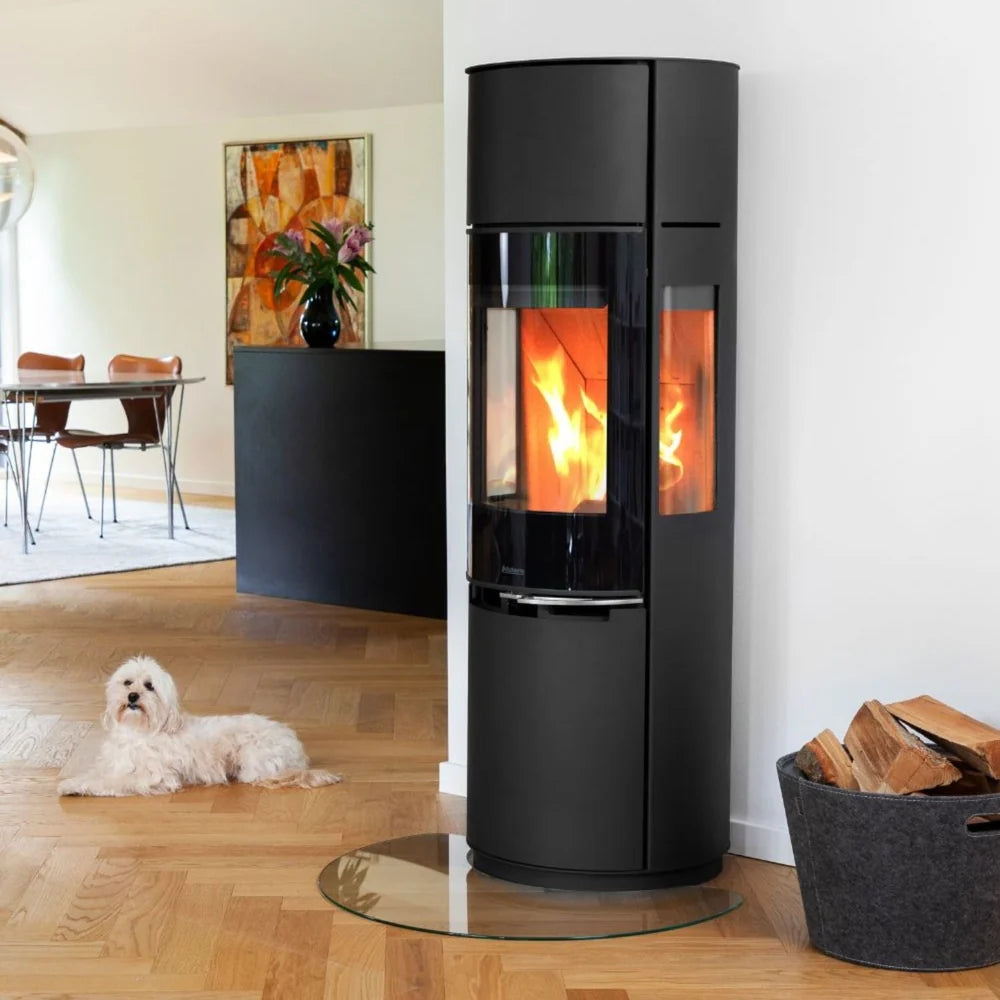 Stilren och hög Aduro 9.7 Lux braskamin placerad på glasskiva i ett ljust vardagsrum