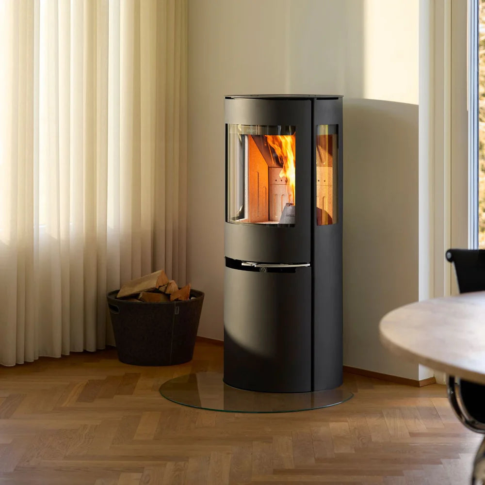 Svart Aduro H1 hybridkamin placerad i ett mysigt rum med parkettgolv