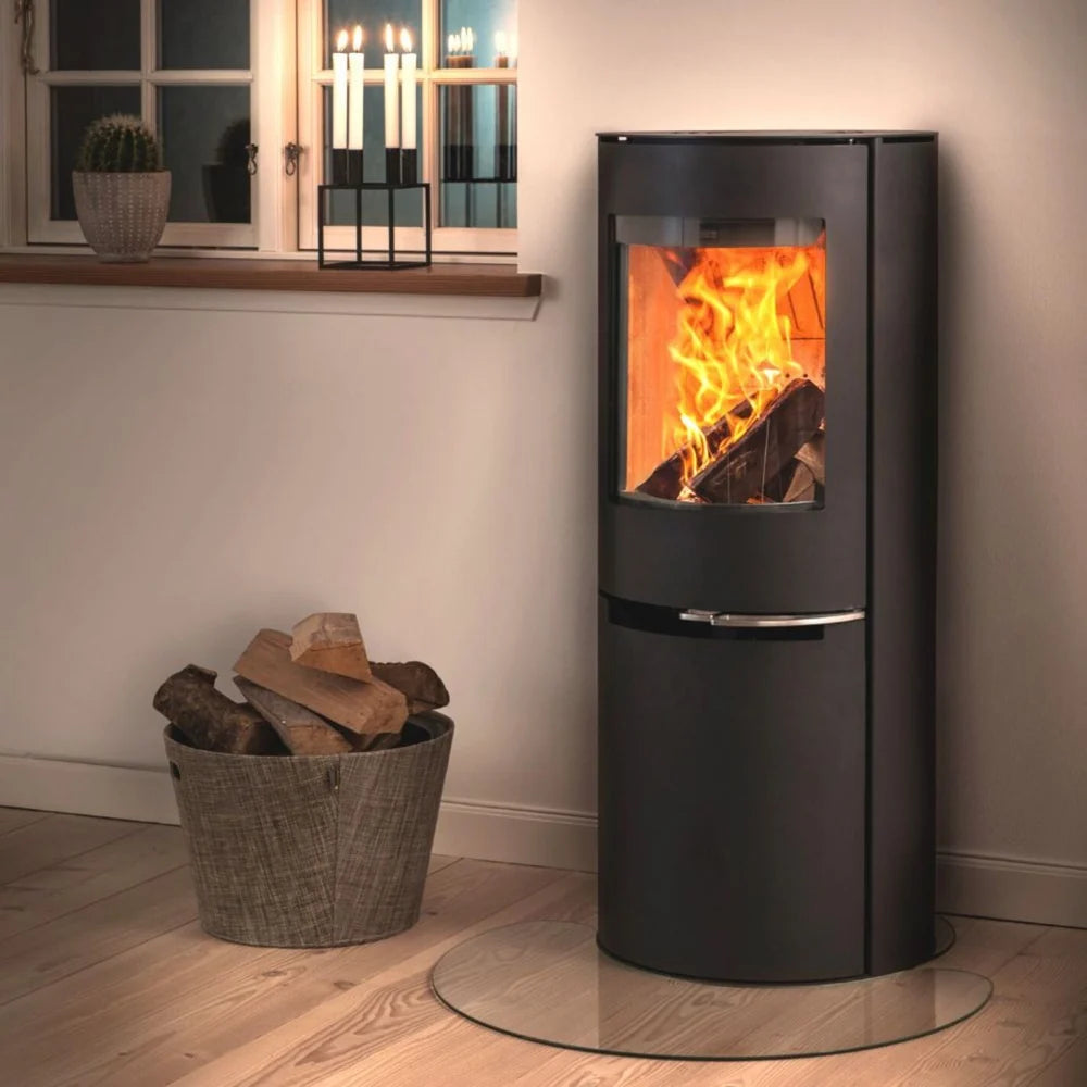 Svart Aduro H2 hybridkamin monterad på glasskiva i ett mysigt hem