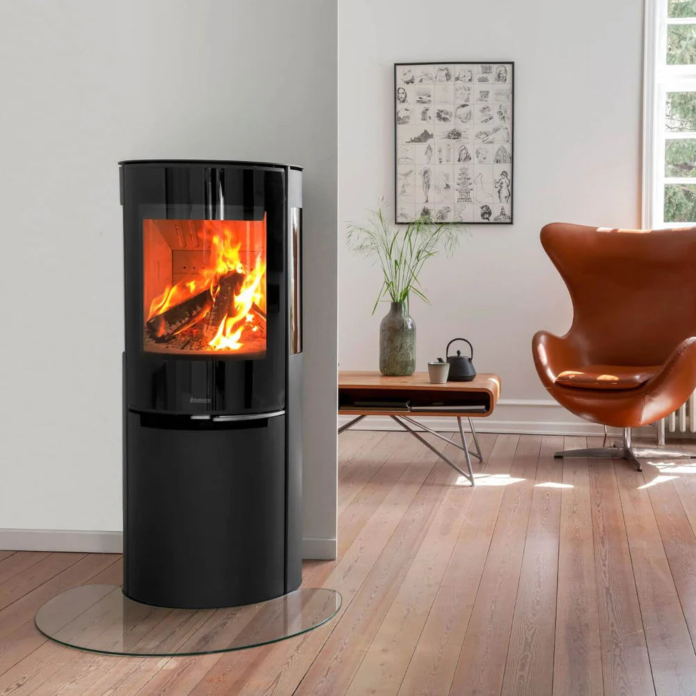 Svart Aduro H3 Lux hybridkamin för pellets och ved monterad i ett vardagsrum med läderfåtölj