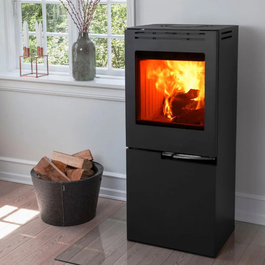 Svart Aduro H5 hybridkamin för pellets och ved placerad i ett ljust vardagsrum vid ett fönster